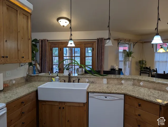 Kitchen featuring a white farmhouse sink, wood-finish cabinetry, granite countertops, and a tile backsplash