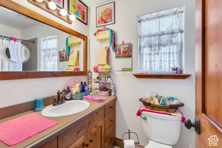 Bathroom featuring a single vanity with wood cabinetry, an integrated sink, and a framed mirror
