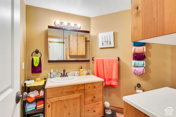 Bathroom featuring a wood-finish vanity with an integrated sink and laminate countertop