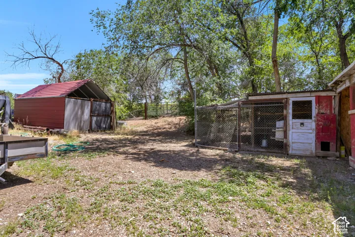 Outdoor area featuring a red metal shed with an open gable end and a separate chicken coop with a fenced run