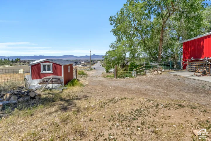 Red shed structure with white trim and window, positioned on a sloped, unpaved lot
