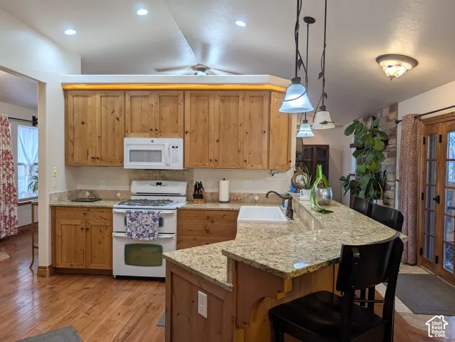 Kitchen featuring wood-finish cabinetry, light-toned granite countertops, white appliances, a built-in microwave, and a white farmhouse-style sink