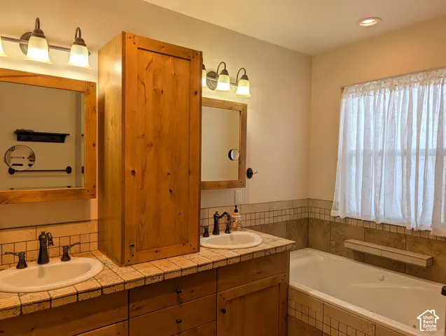 Dual vanity with wood-finish cabinetry, integrated sinks, and bronze-finish fixtures