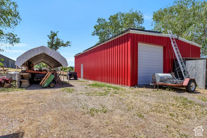 Red metal-sided outbuilding featuring a 12' white roll-up door and a single entry door