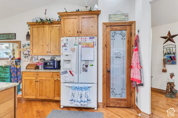 Kitchen featuring wood cabinetry, granite-style countertops, natural hickory flooring, and a pantry door with etched glass