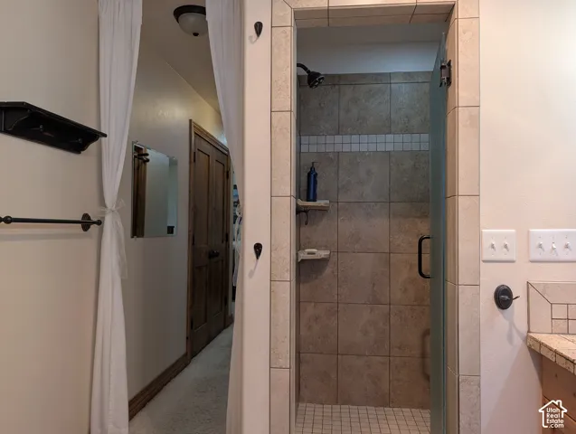 Tiled shower with glass enclosure, integrated shelving, and a dark bronze showerhead