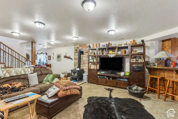 Lower level living area featuring a wood stove with a stone surround, built-in shelving, a wooden bar, and carpeted flooring
