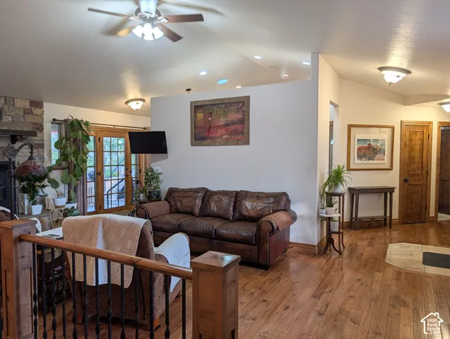 Living area featuring wood-finish flooring, a stone fireplace surround, and recessed ceiling lighting