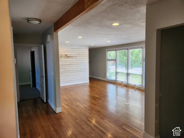 Expansive interior featuring wood flooring, recessed lighting, a decorative wood accent wall, and large windows with blinds