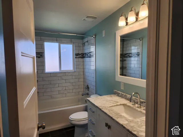 Bathroom featuring a white vanity with a stone countertop, an undermount sink, and a framed mirror with a three-bulb vanity light
