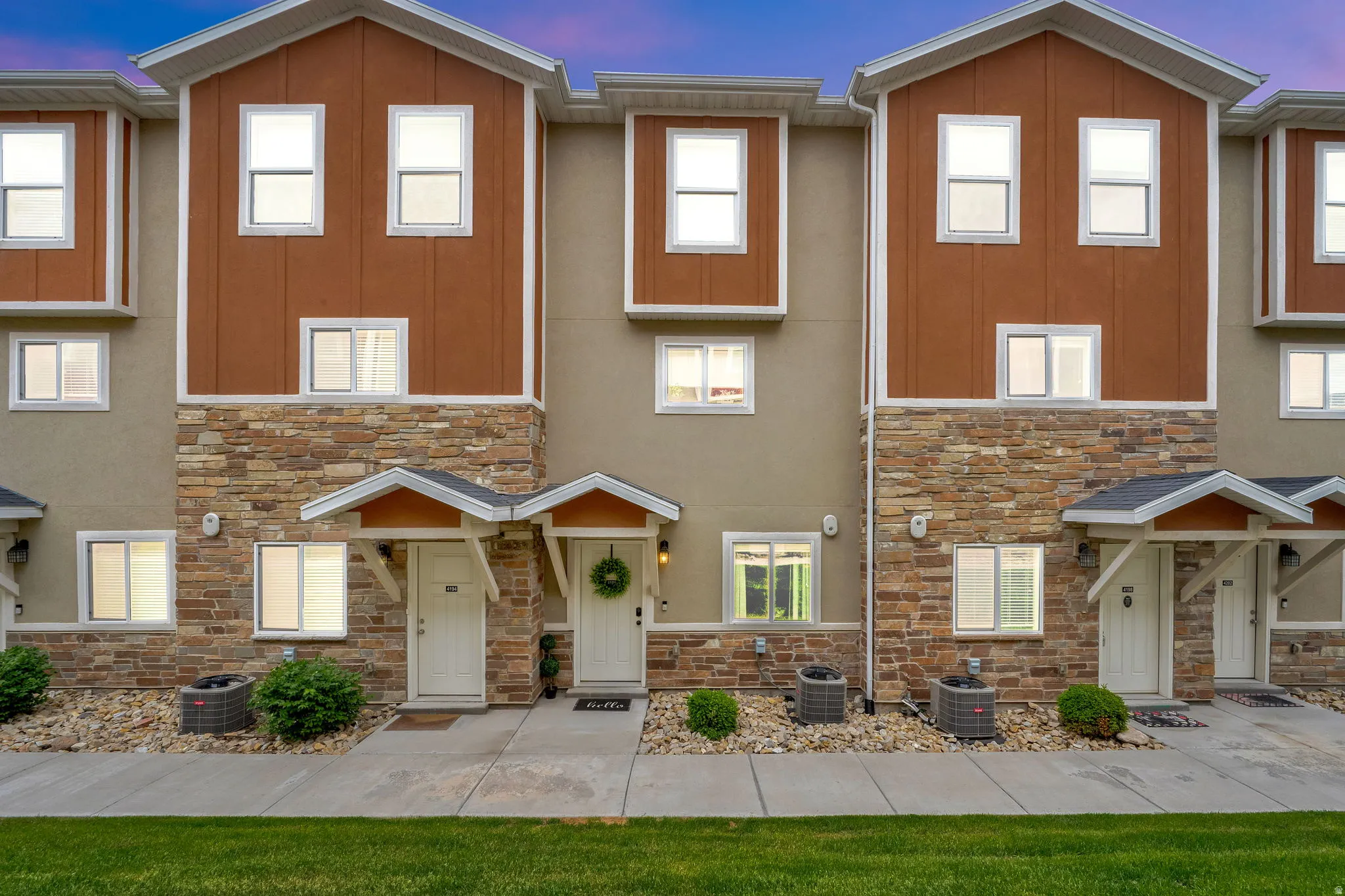 Townhome exterior featuring earth-toned stucco and brown vertical siding