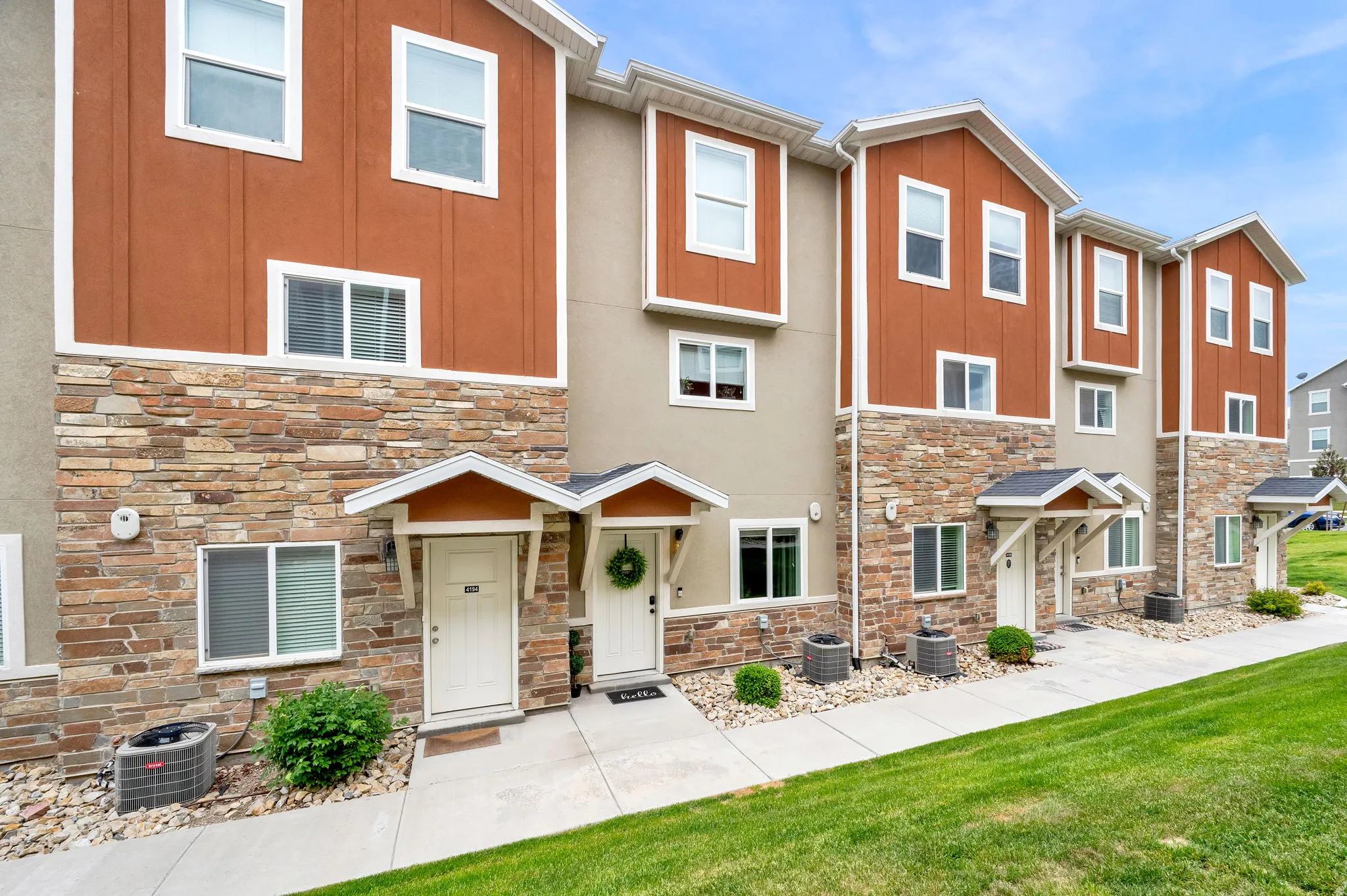 Multi-story townhome exterior featuring stone veneer and vertical siding accents