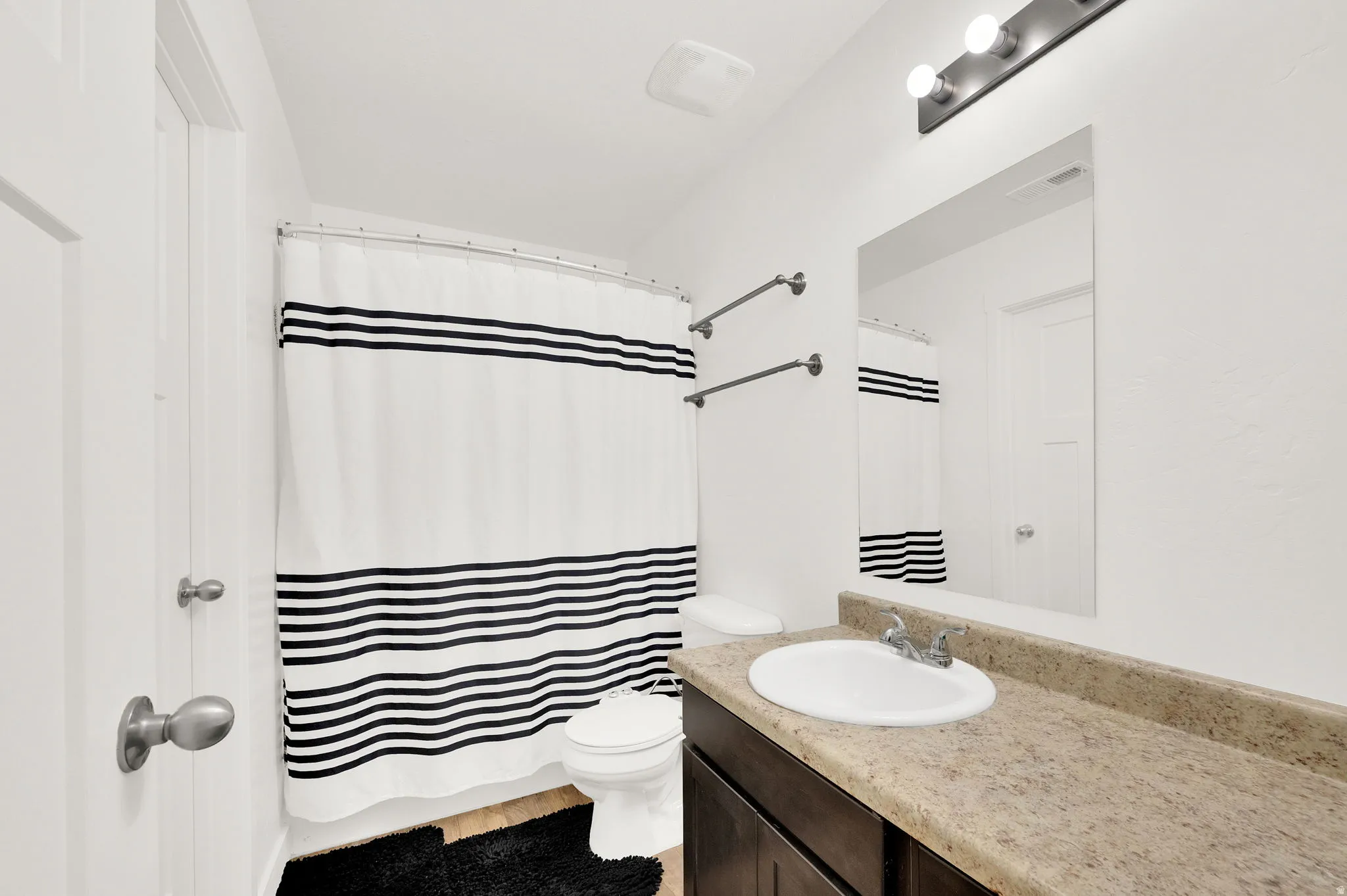 Bathroom featuring a shower/tub combination, a vanity with a light-toned countertop, a rectangular mirror, and a wall-mounted light fixture