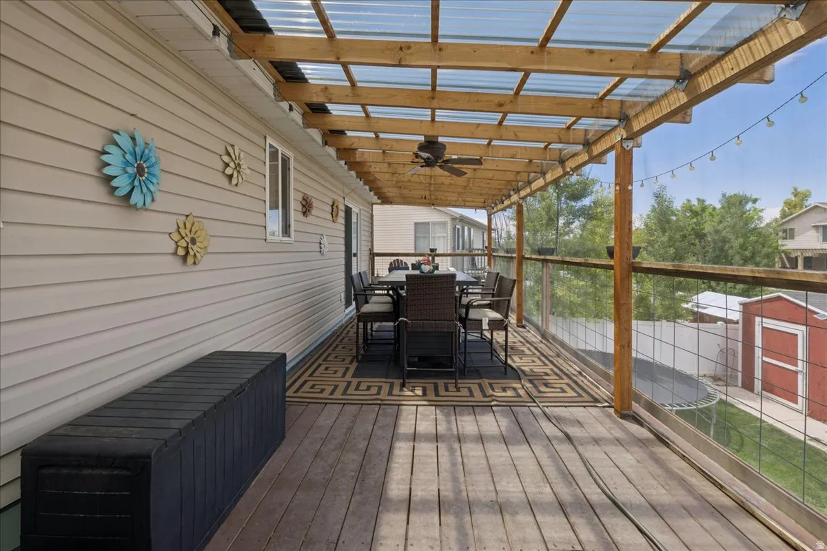 Expansive exterior deck featuring wood-finish flooring, a transparent panel roof, and a ceiling fan