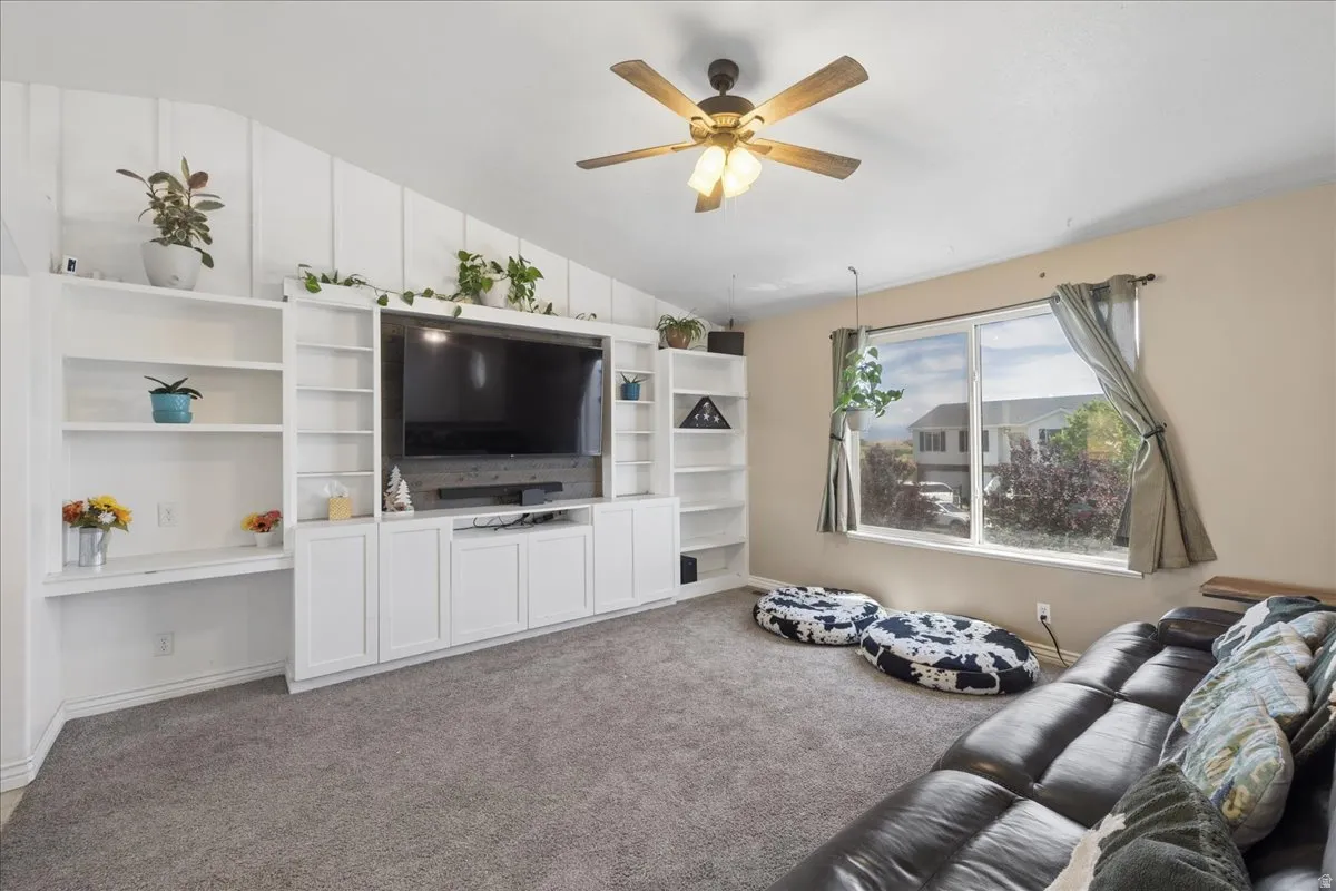 Living area featuring a spacious built-in entertainment center, vaulted ceilings with wood paneling, and neutral-toned carpeting