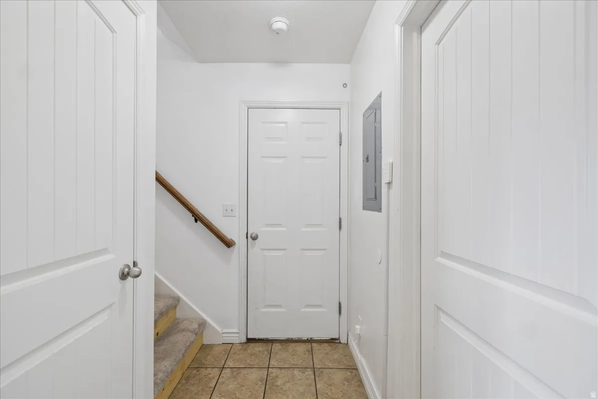 Foyer featuring ceramic tile flooring, a carpeted staircase with wood handrail, and white panel doors