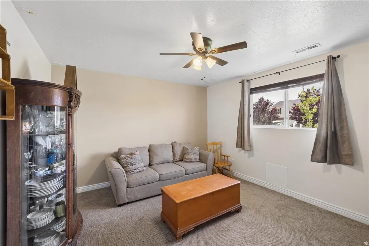 Carpeted room with neutral paint, featuring a ceiling fan with integrated lighting