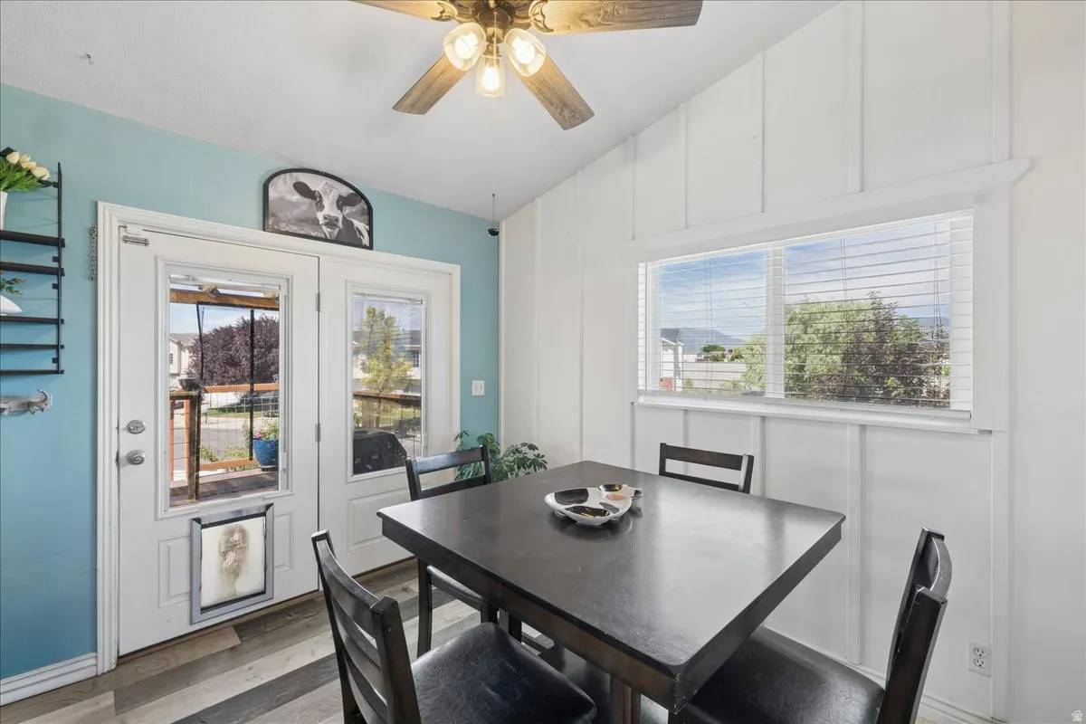 Vaulted ceiling dining area featuring wood-finish flooring and a ceiling fan with light fixture