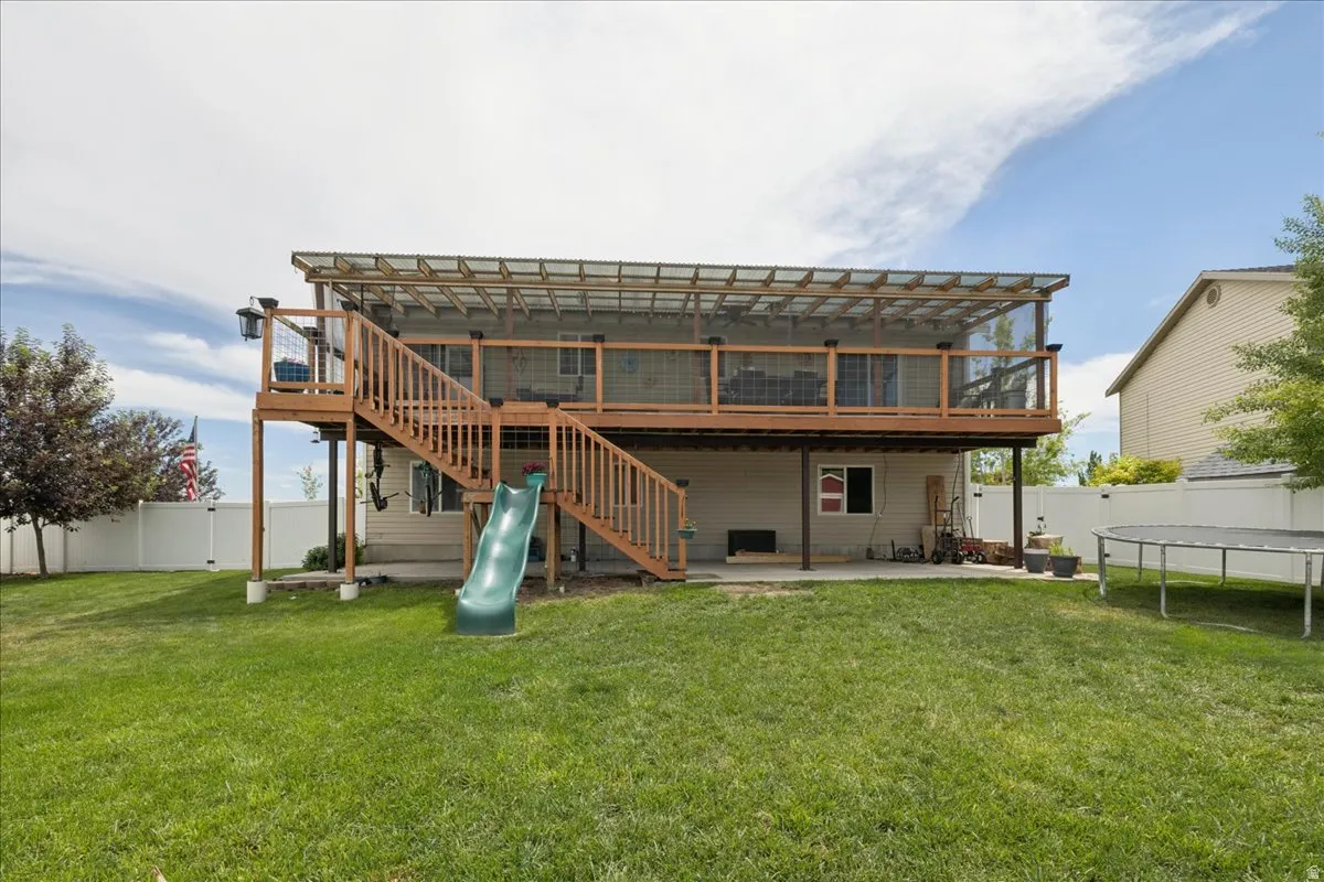 Expansive fenced backyard featuring a two-story wood deck with screened upper level, and a lower-level concrete patio