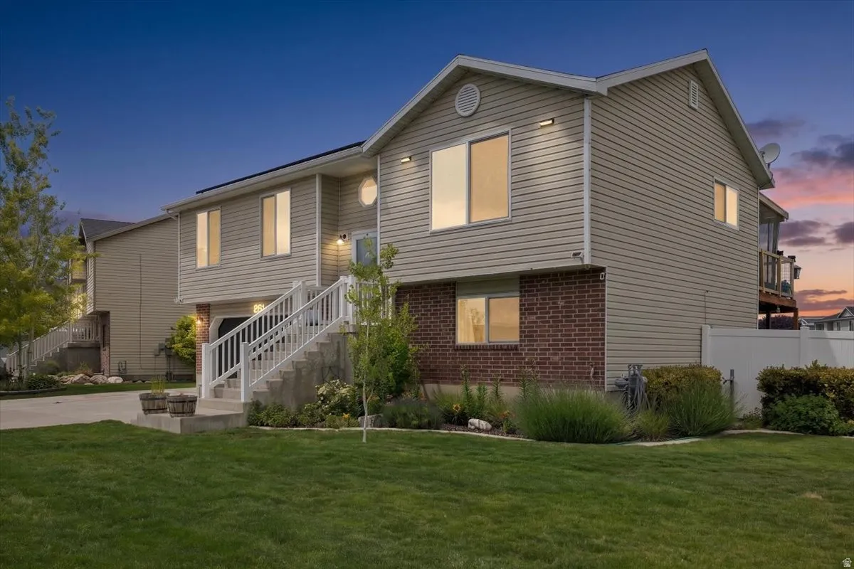 Two-story home featuring light-toned siding and a brick-finish lower level