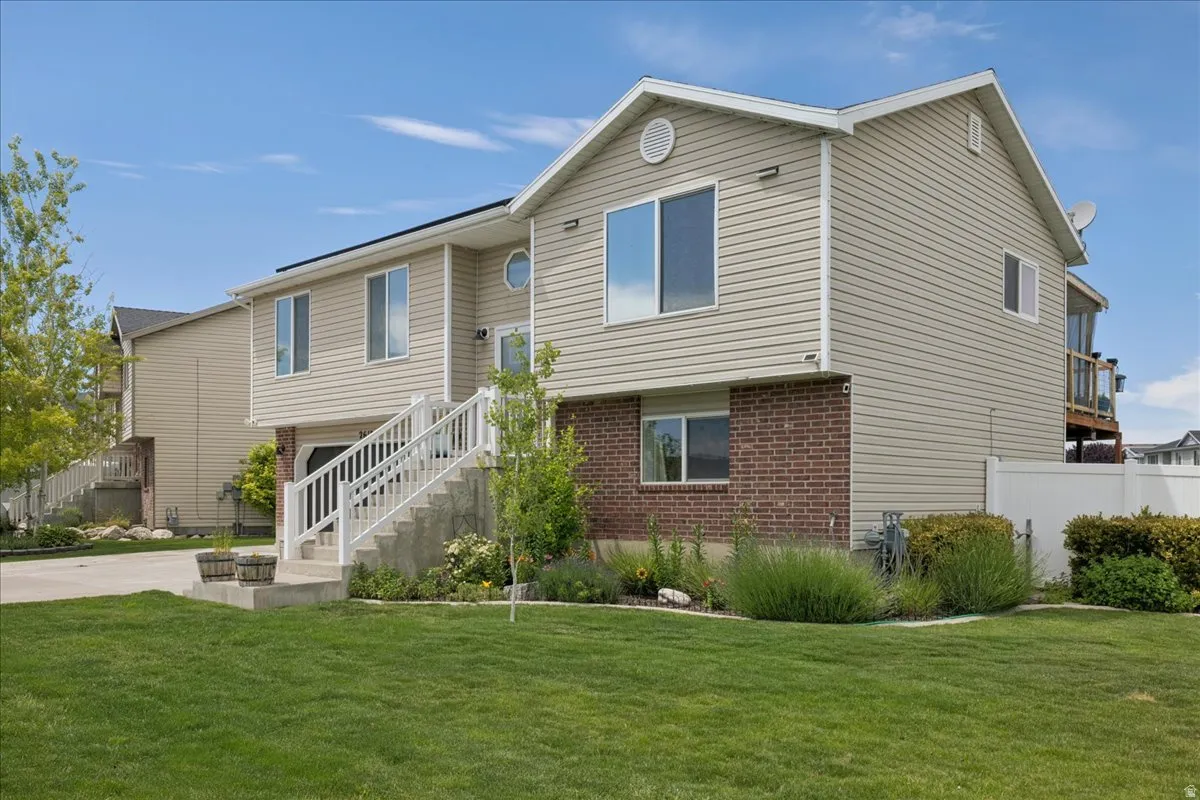 Split-level residence featuring a brick and siding facade, a front-facing garage, and a concrete staircase with white railings
