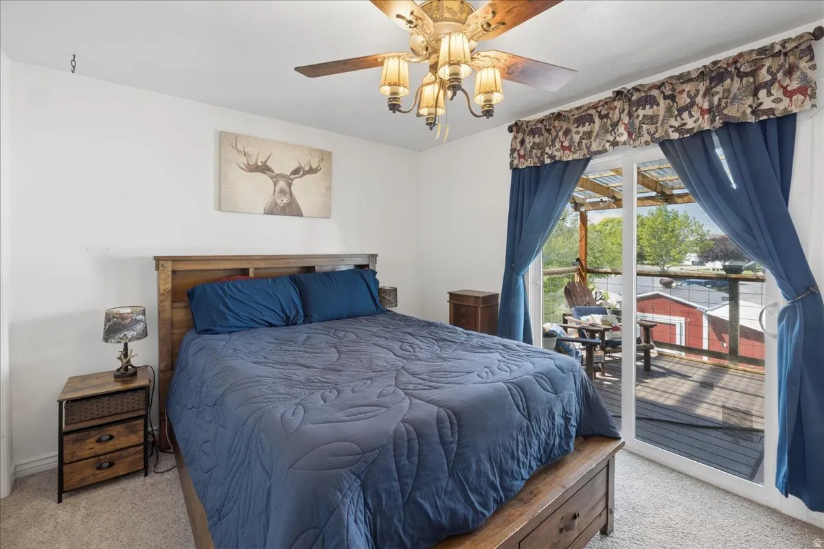 Bedroom featuring a sliding glass door to an outdoor deck, a ceiling fan with integrated lighting, and carpet flooring