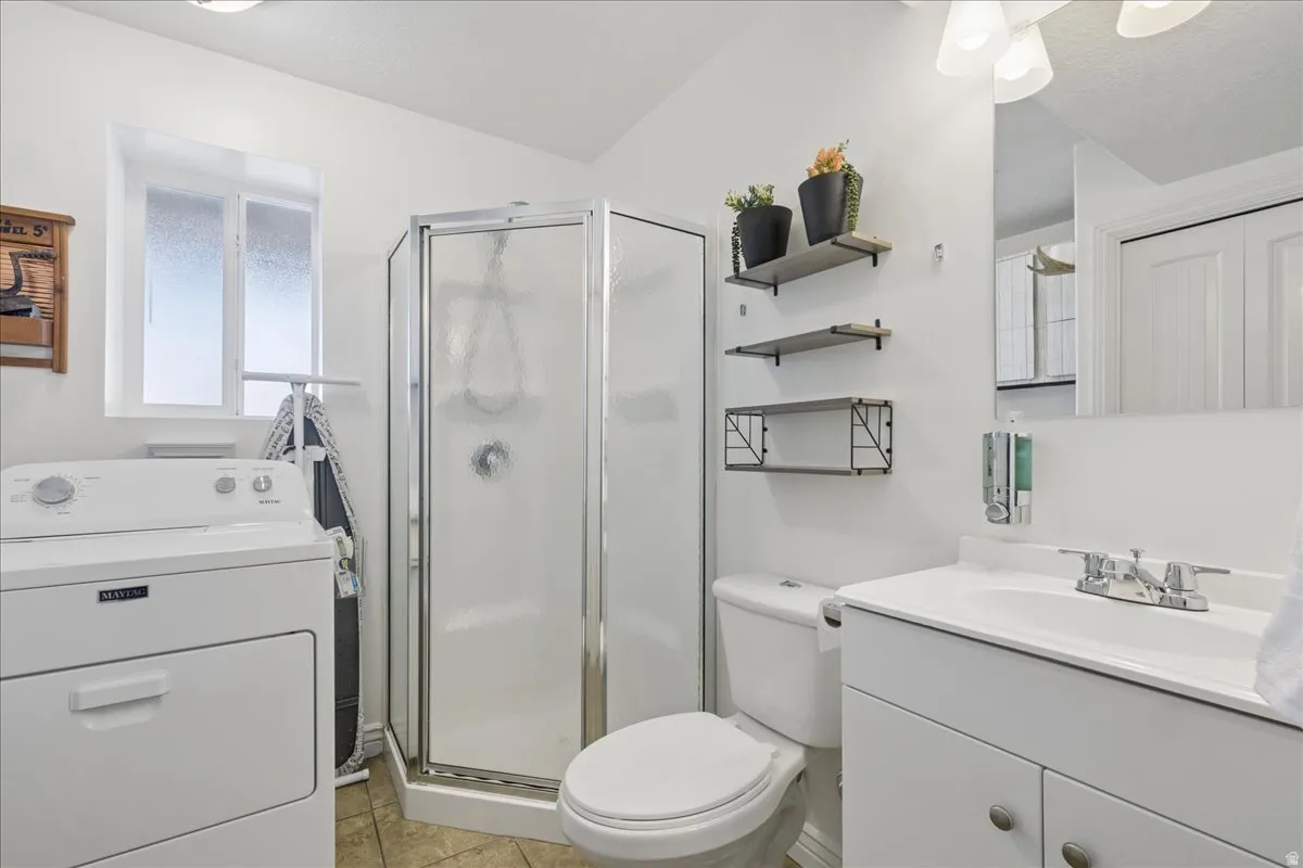 Bathroom featuring a glass-enclosed shower, white vanity with integrated sink, and wood-finish flooring