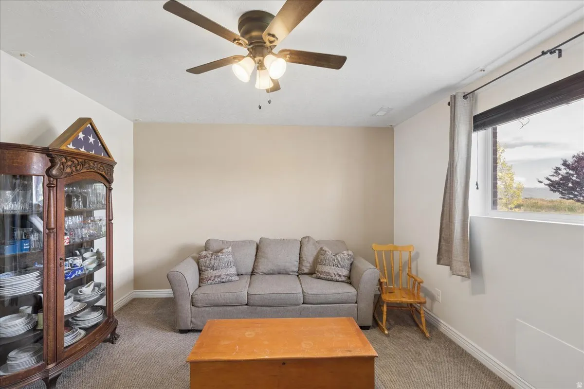 Spacious room featuring carpeted flooring, neutral wall tones, and a ceiling fan with integrated lighting