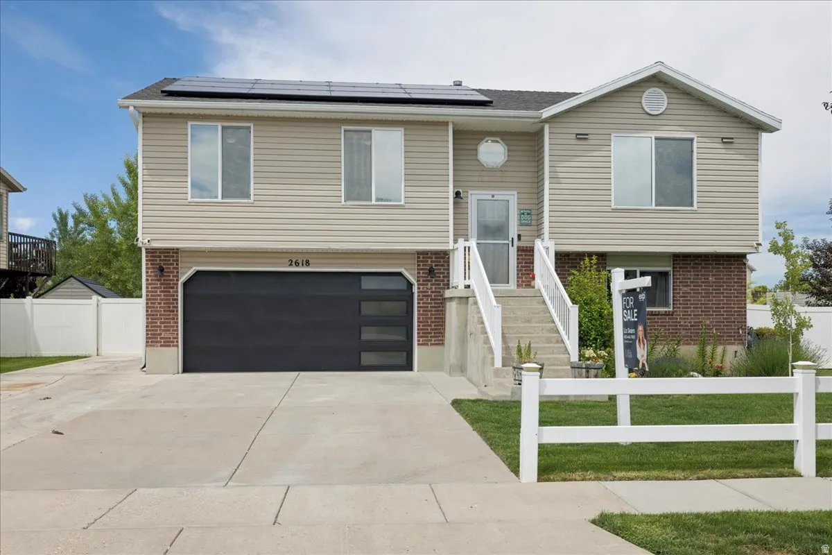 Two-story residence featuring light-toned siding, brick accents, and a dark garage door with horizontal window panels
