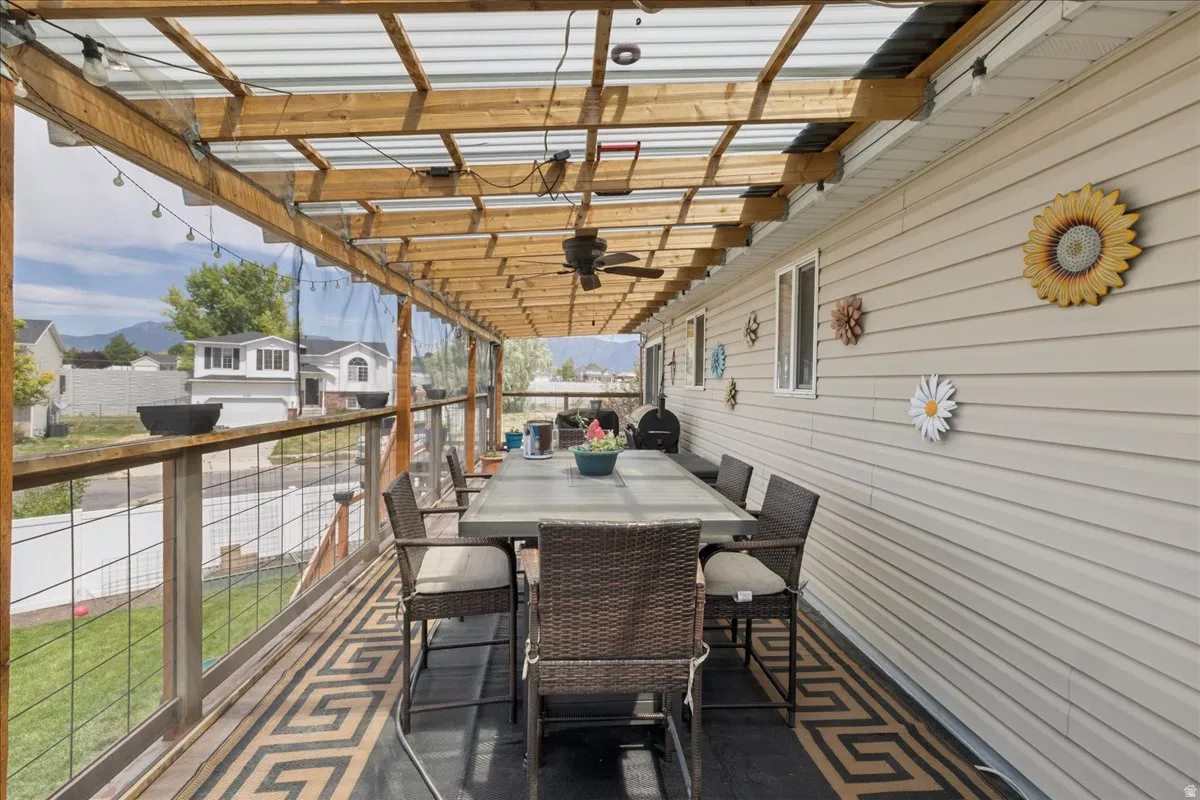 Expansive covered deck featuring a transparent roof, wood-finish support beams, string lighting, and a ceiling fan