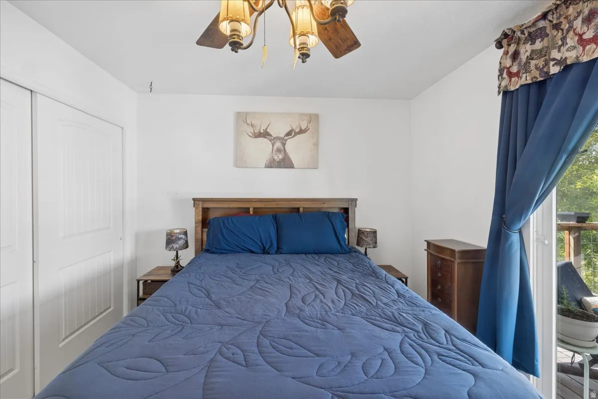 Bedroom featuring a wood-finish headboard, white walls, and a ceiling fan with integrated lighting