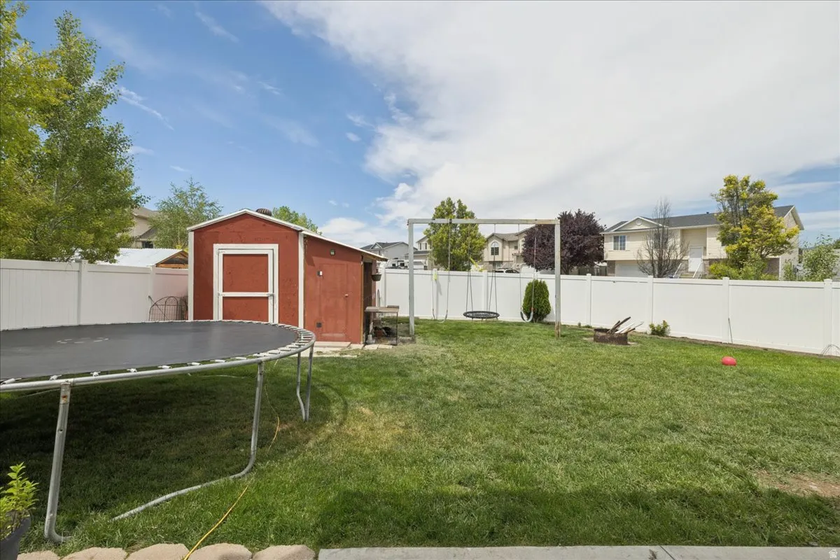 Expansive backyard featuring a manicured lawn, a red storage shed, and a swing set