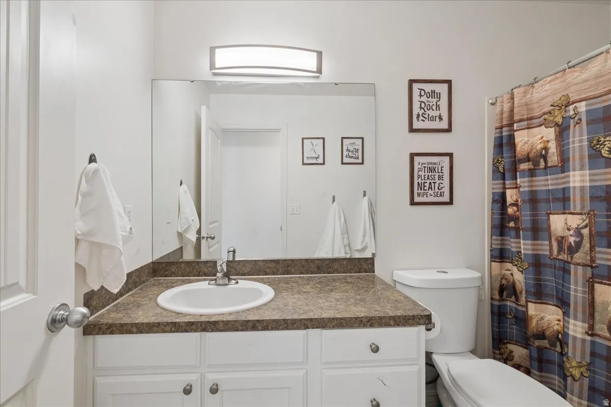 Bathroom featuring a white vanity with panel cabinetry and silver-tone hardware, topped with a speckled countertop