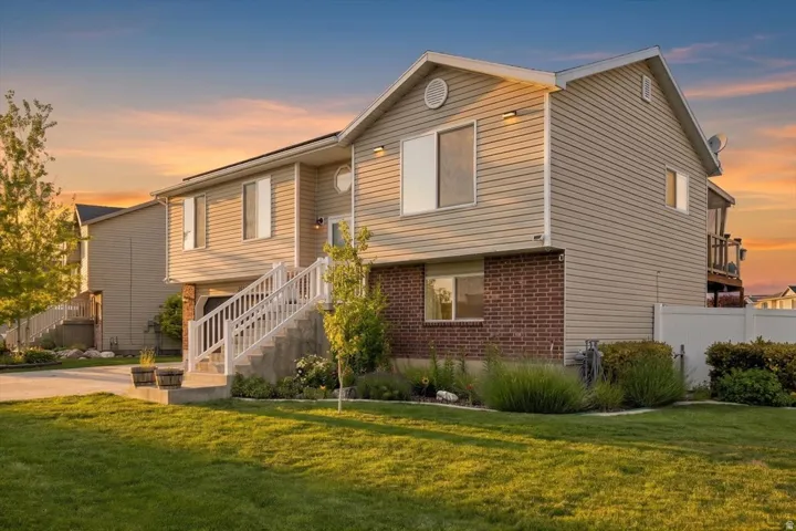Split-level residence featuring beige horizontal siding and brick accents