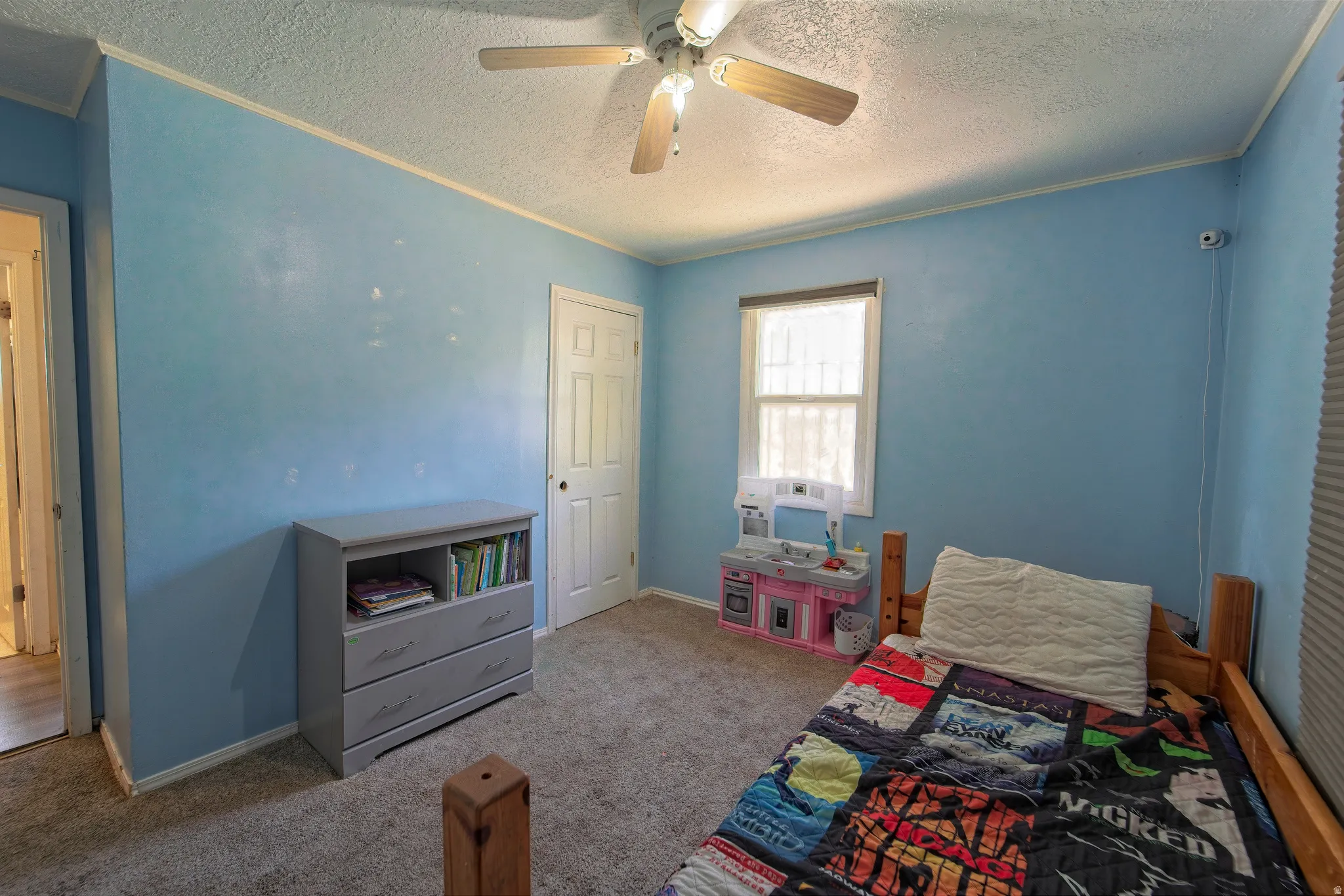 Carpeted room featuring a ceiling fan, a window with blinds, and light blue walls
