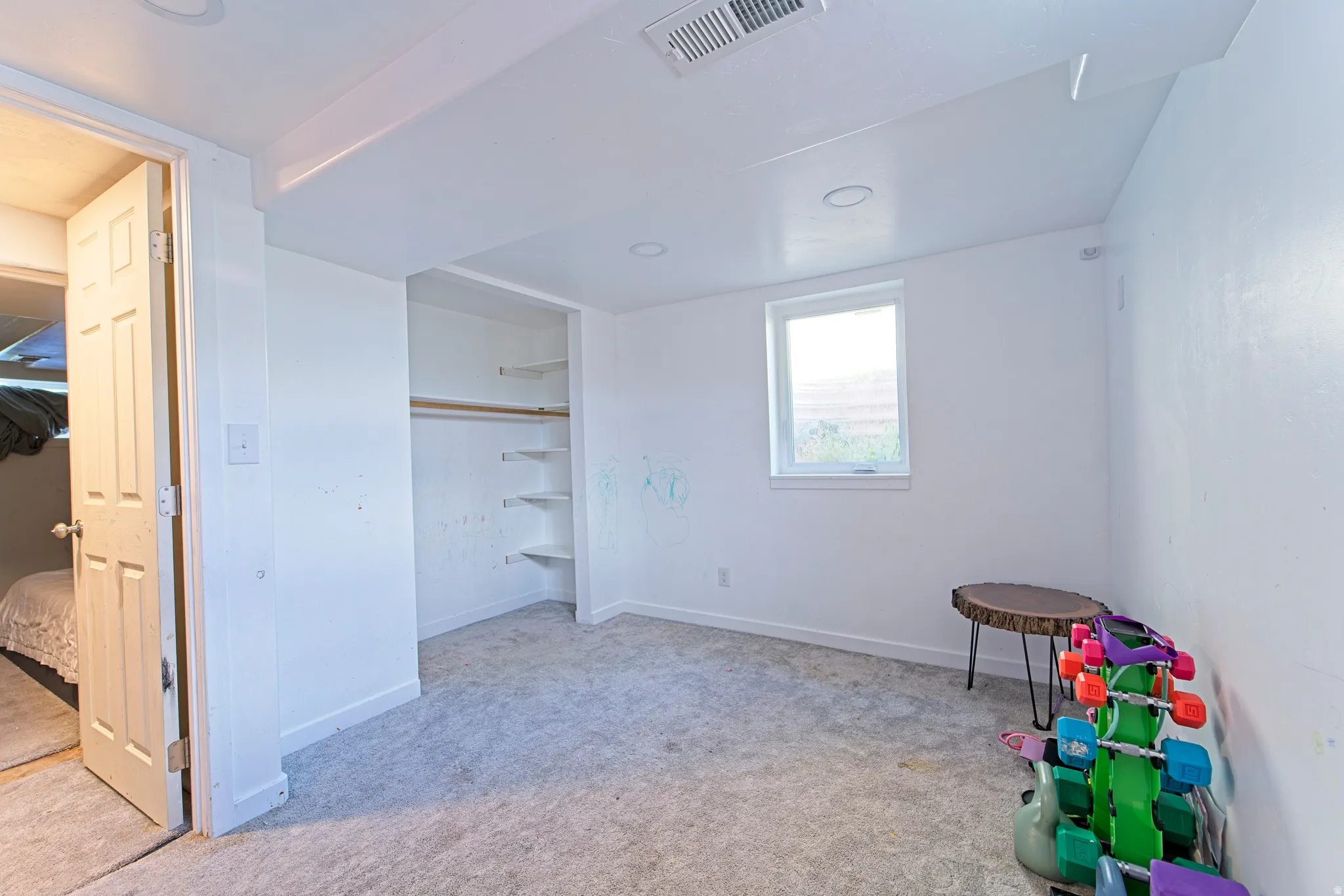 Room featuring light gray carpeting, a window with white trim, and white painted walls