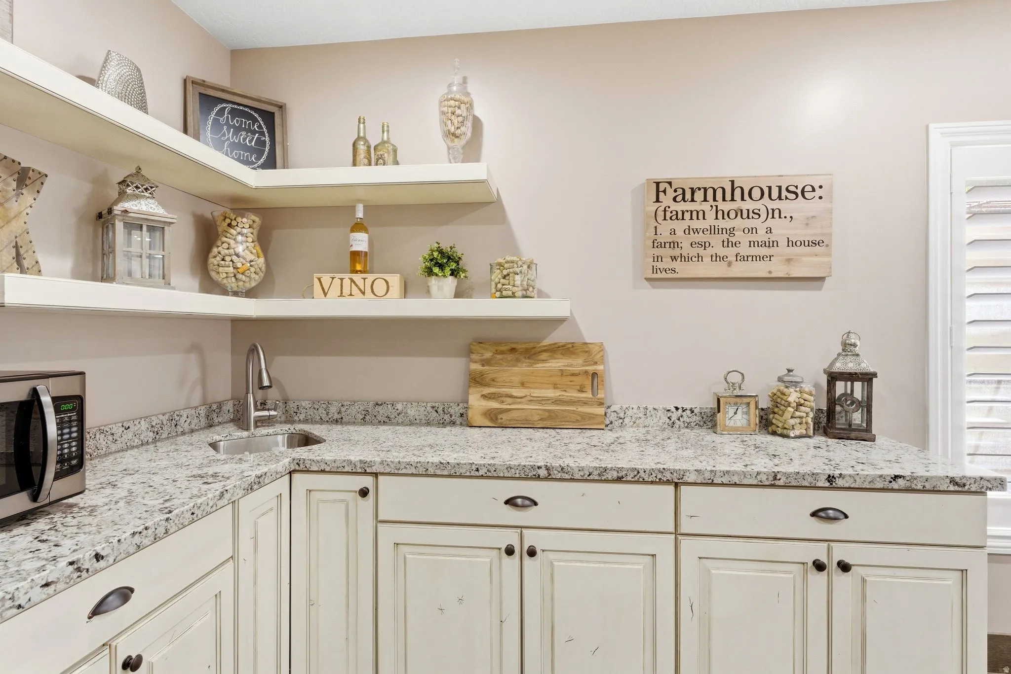 Corner wet bar featuring light-toned cabinetry, speckled countertops, a built-in sink and open shelving