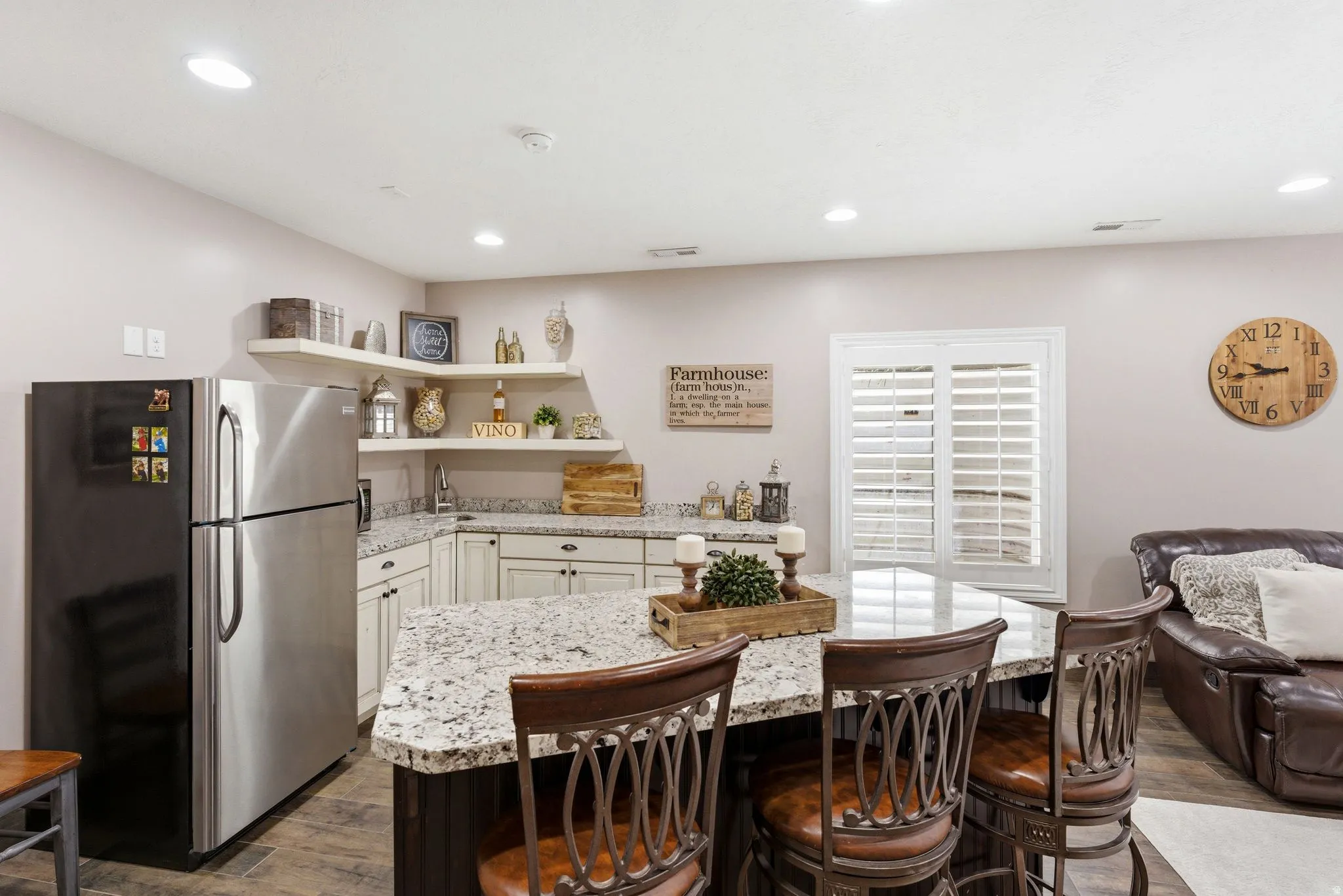 Kitchenette featuring a stainless steel refrigerator, white shaker-style cabinetry, granite countertops, and open corner shelving