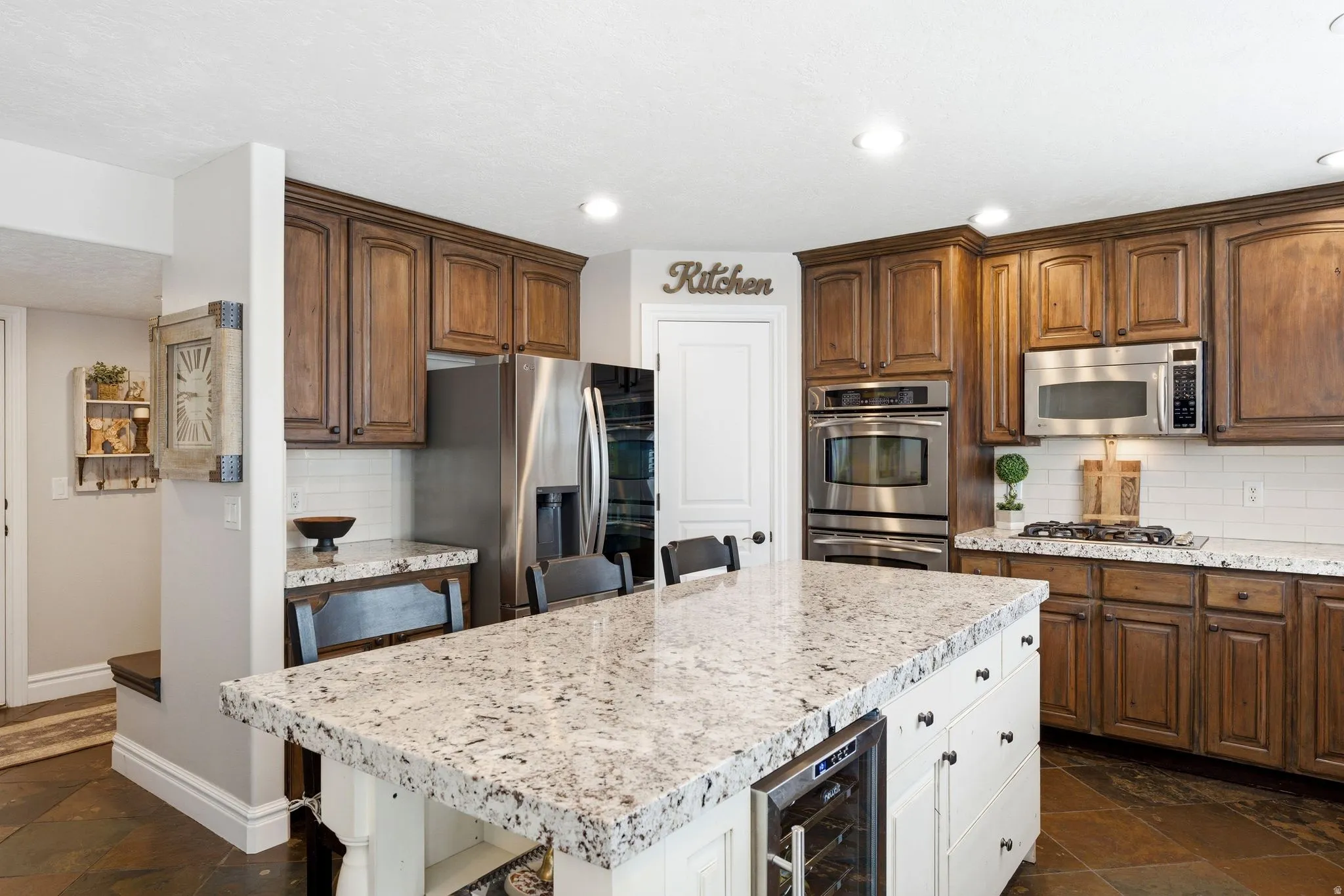 Spacious kitchen featuring an expansive island with a granite countertop and built-in wine fridge