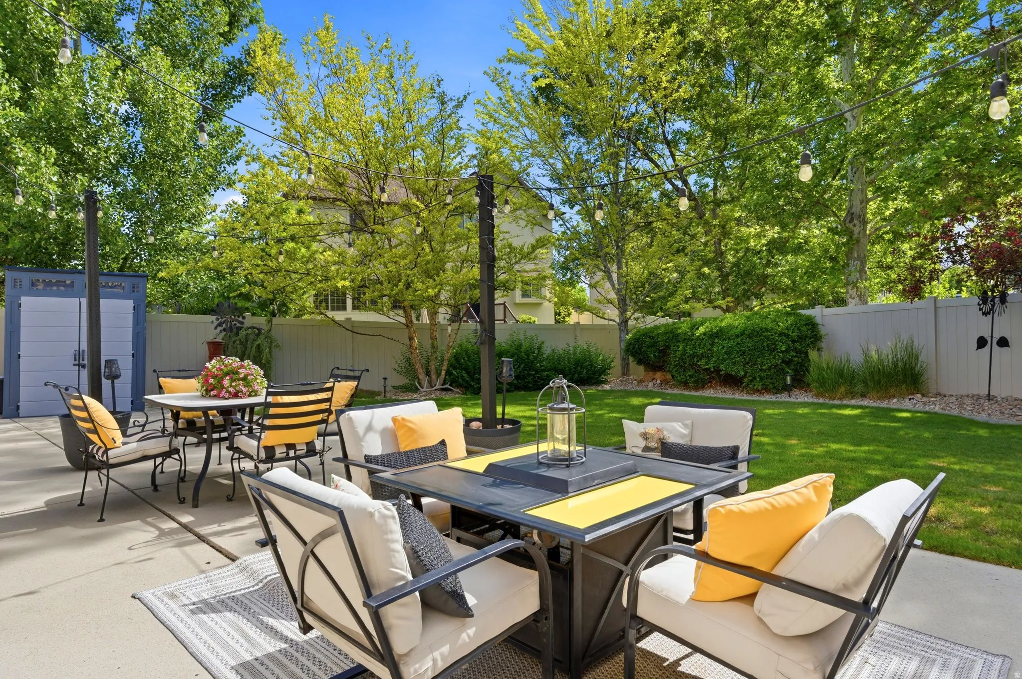 Expansive concrete back patio are with manicured lawn and mature trees