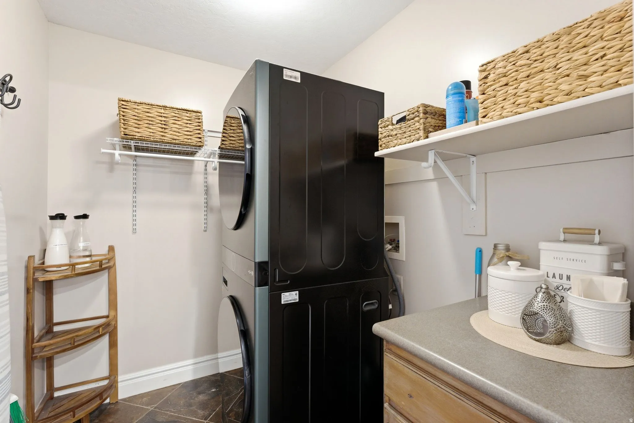 Laundry area featuring a stacked washer and dryer, countertop space, and built-in shelving