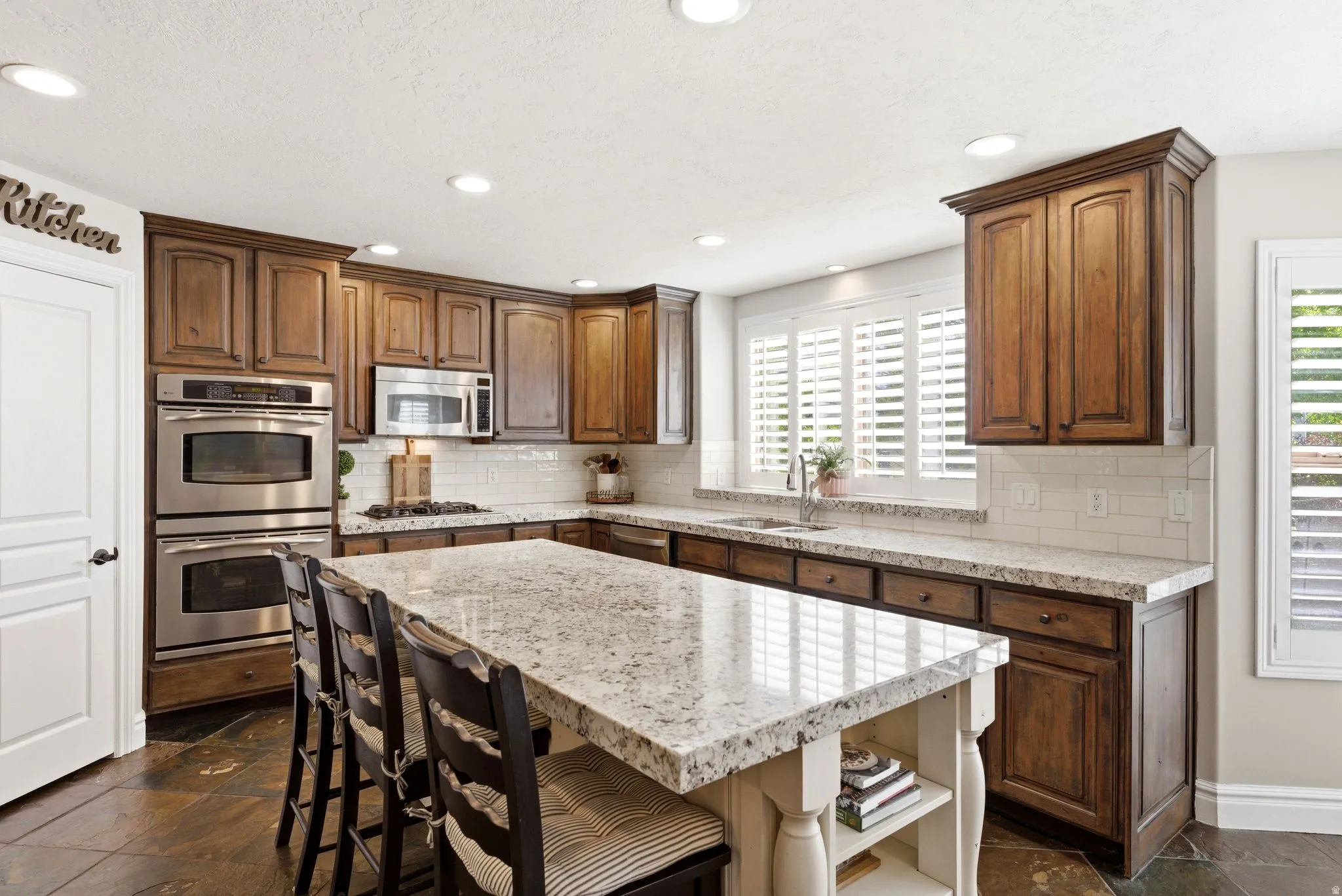 Spacious kitchen featuring an expansive granite island with seating