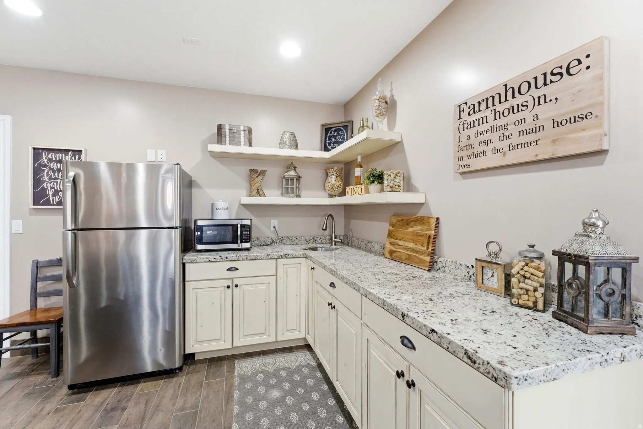 Kitchenette featuring L-shaped granite-style countertops, wood-finish flooring, recessed lighting and shaker-style cabinetry