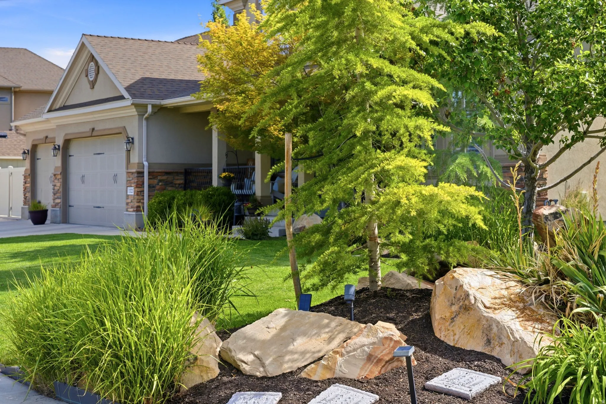 Front of home showcasing landscaping, three-car garage and covered porch