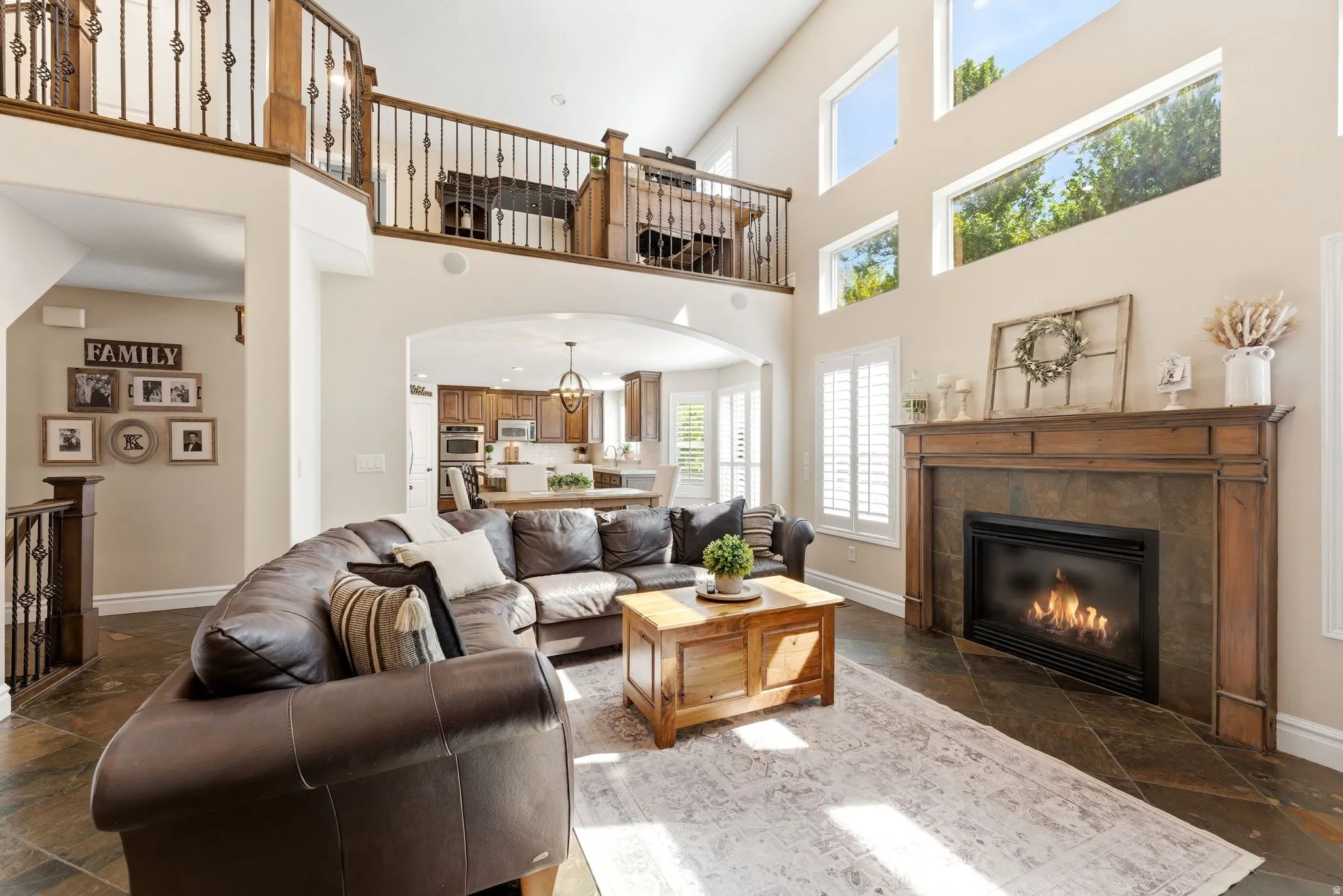 Two-story living area featuring a fireplace with a wooden mantel, multiple windows, and an upper-level loft