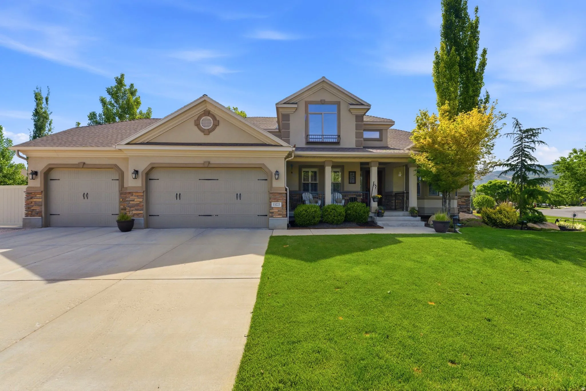 Front of home featuring a covered front porch, a three-car garage, and a large driveway