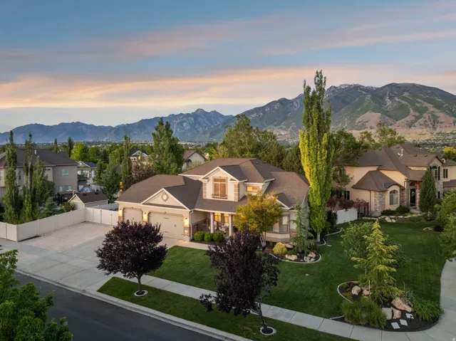 Two-story residence featuring a three-car garage, large RV parking for multiple vehicles, manicured front lawn, and mature landscaping