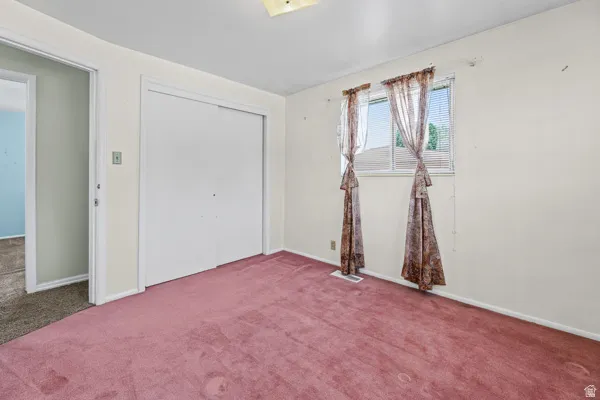 Room featuring wall-to-wall carpeting, dual windows, and a built-in closet with sliding doors