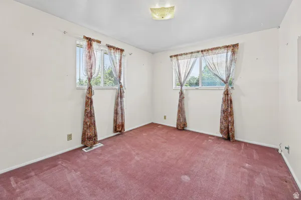 Room featuring neutral painted walls, two windows, and red carpet flooring