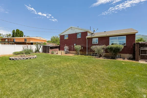 Expansive green lawn with a structured garden bed and a white vinyl fence